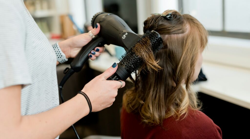 woman in red long sleeve shirt holding hair blower